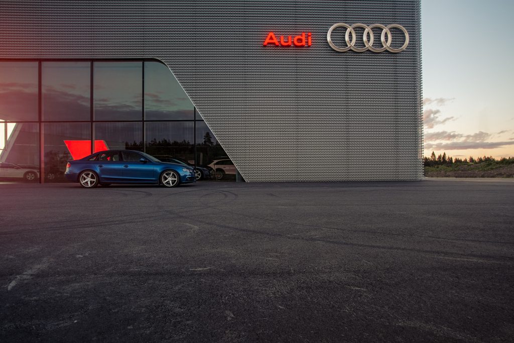 blue porsche 911 parked beside white wall