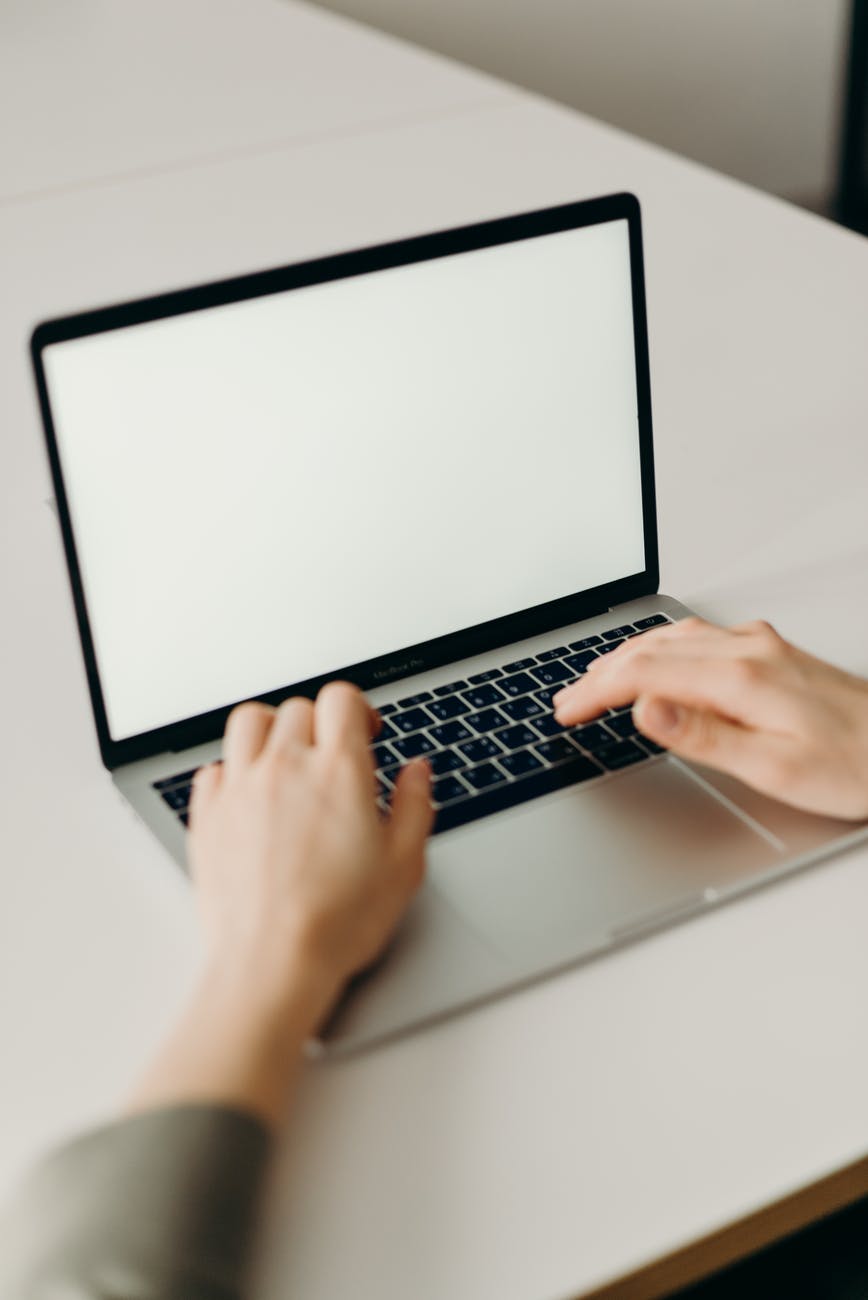 person using macbook pro on white table