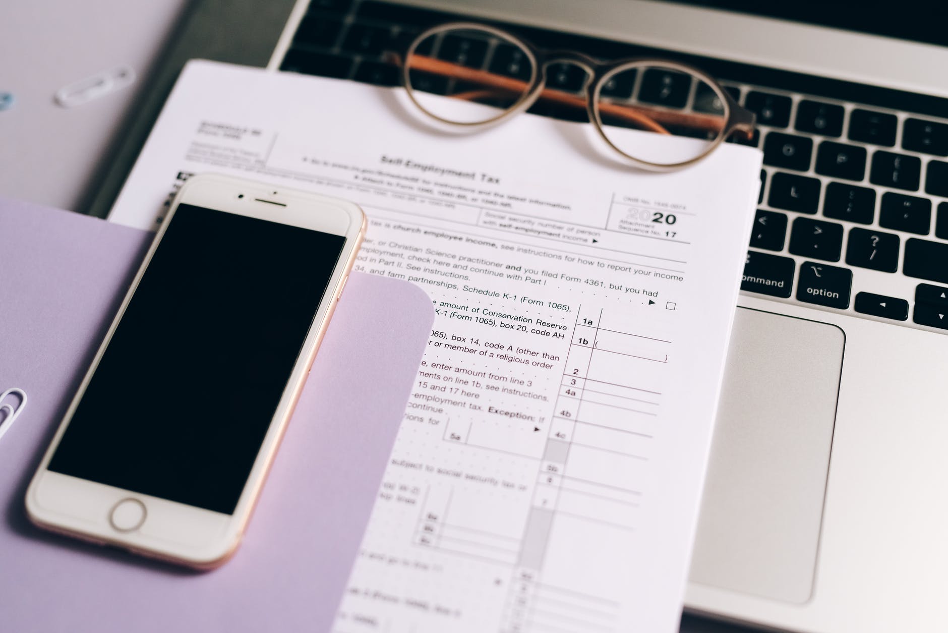 a mobile phone near the documents and laptop on the table