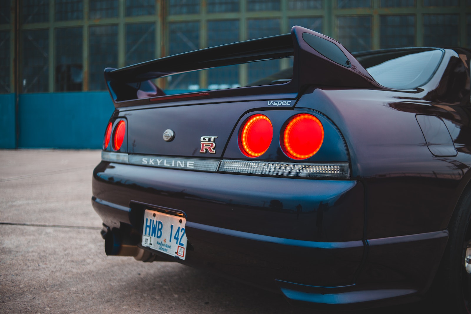 Sports automobile with bright taillights and license plate on bumper parked near urban building