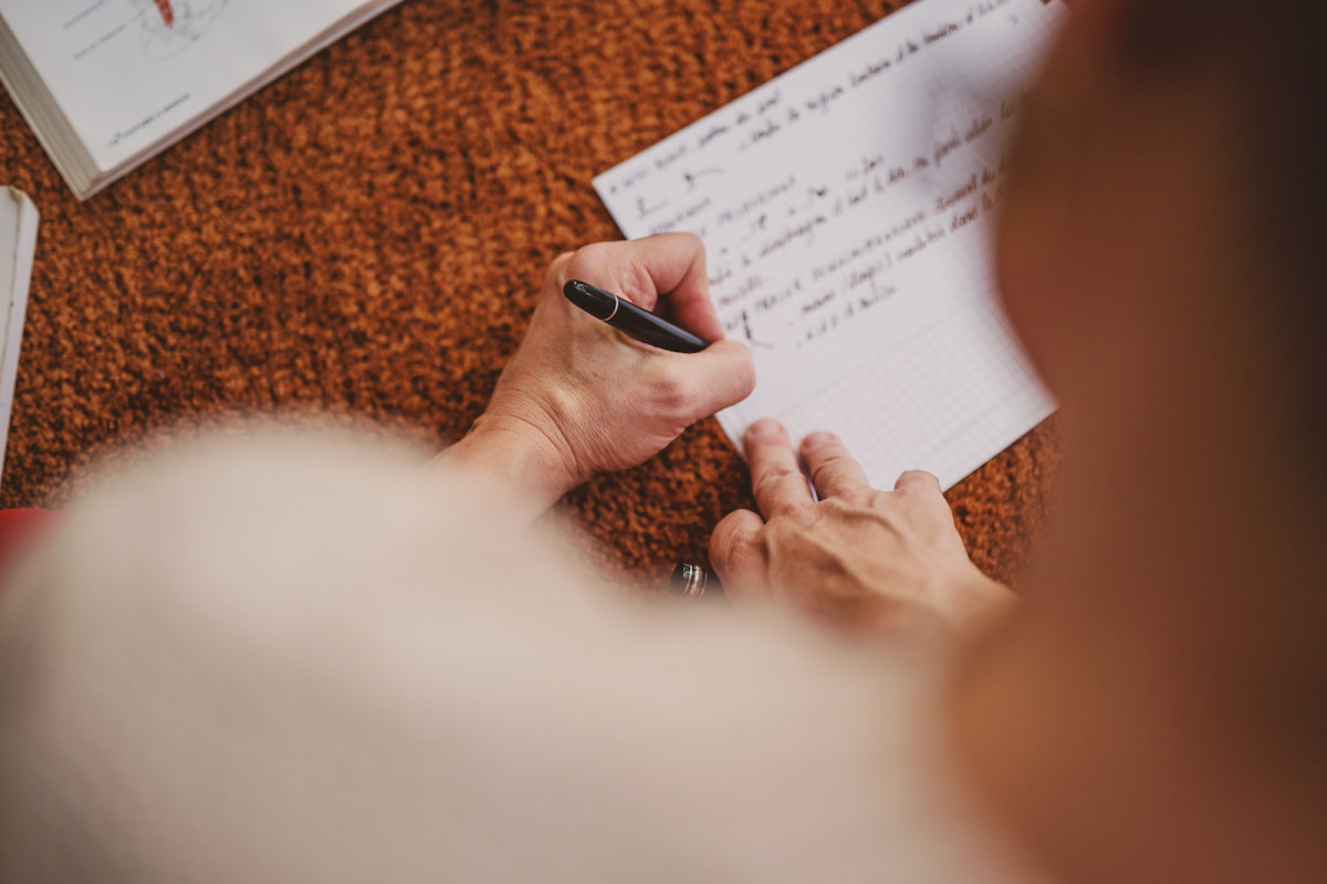 person holding black pen on white book page