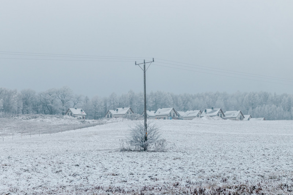 a snow covered field with a telephone pole in the foreground