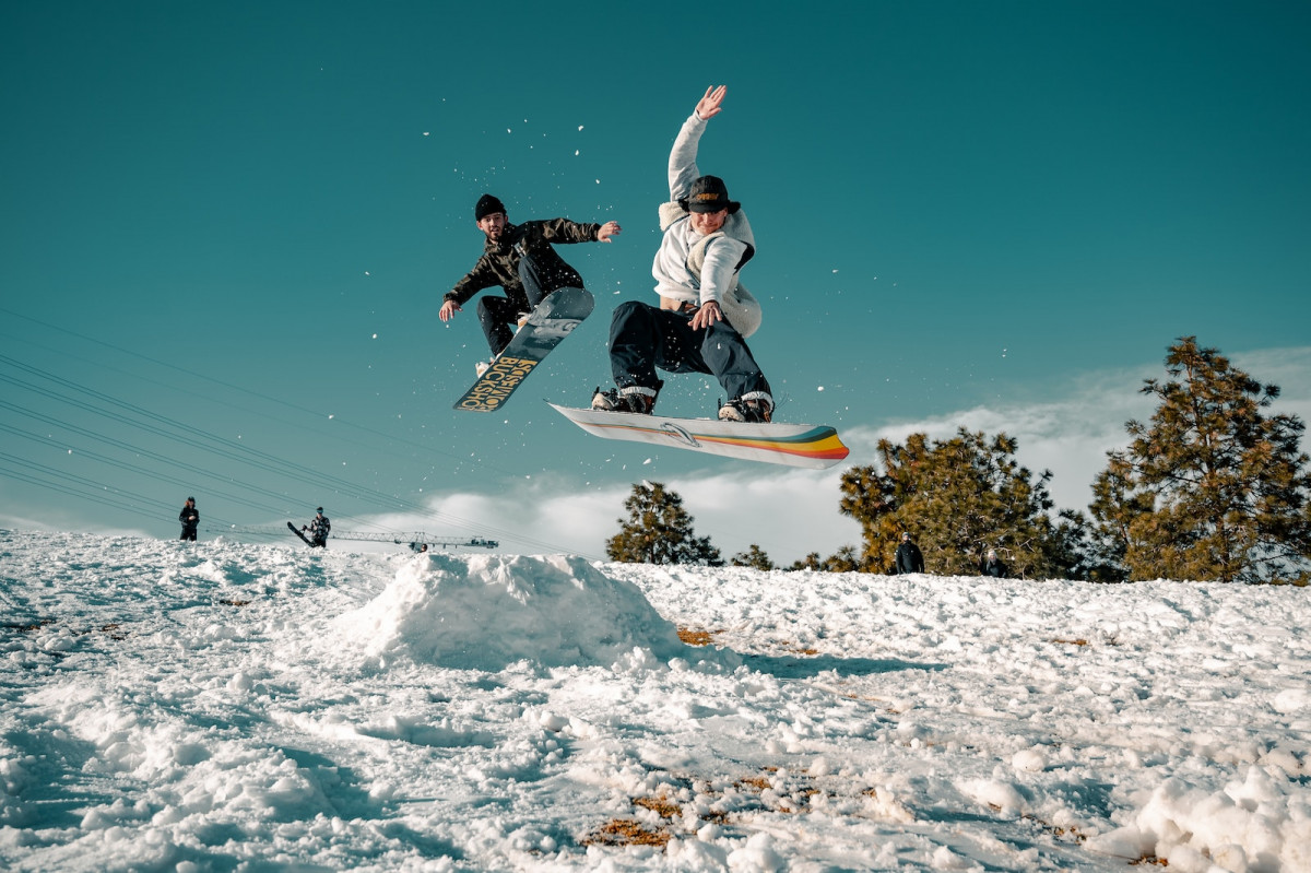 man in black and white jacket riding on snowboard during daytime