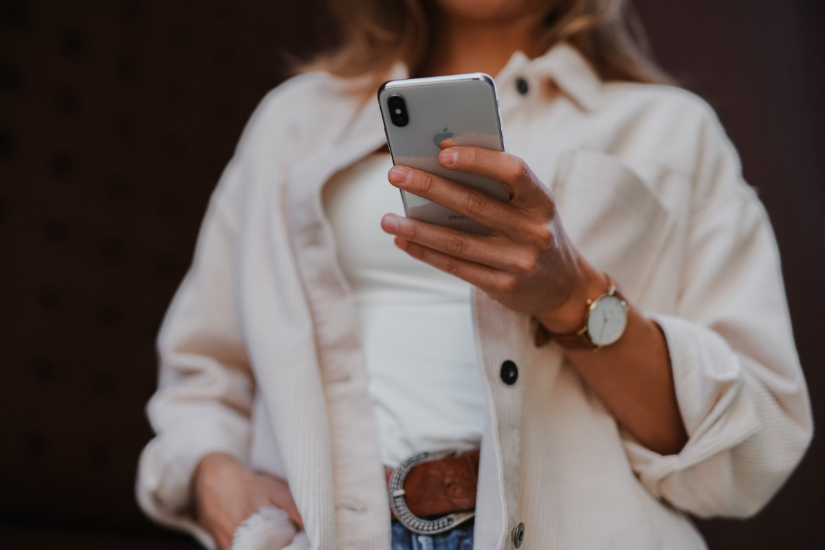 woman in white coat holding silver iphone 6. mobile validation
